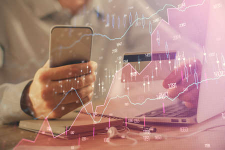 Double exposure of man hands holding a credit card and Forex graph drawing. Stock trading and...