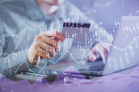 Double exposure of man hands holding a credit card and Forex graph drawing. Stock trading and...
