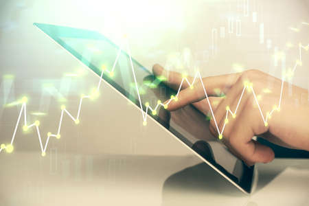 Multi exposure of mans hands holding and using a digital phone and forex graph drawing. Financial...