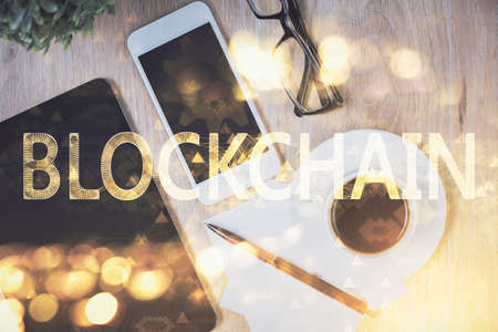 Double exposure of blockchain theme hologram over table with phone. Top view. Crypto technology concept.の写真素材