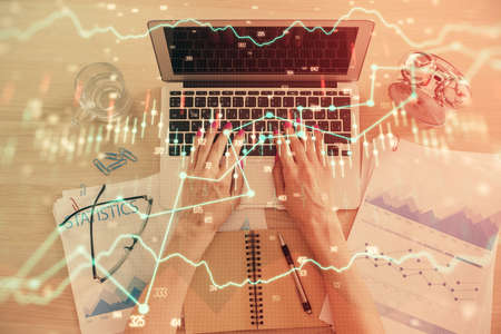 Double exposure of woman hands working on computer and forex graph hologram drawing. Top View....