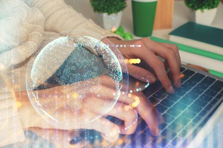 Double exposure of woman hands working on computer and world map hologram drawing. International technology business concept.の写真素材