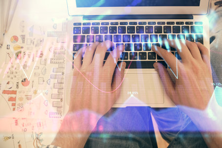 Double exposure of mans hands typing over laptop keyboard and forex chart hologram drawing. Top view. Financial markets concept.の写真素材