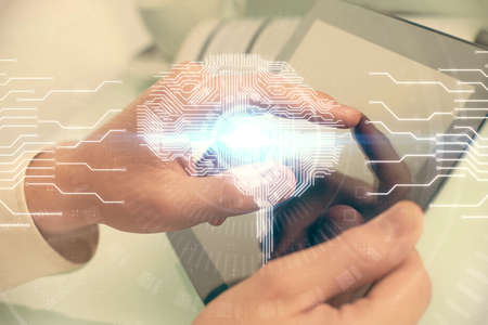 Double exposure of mans hand holding and using a digital device and brain hologram drawing. Data concept.の写真素材
