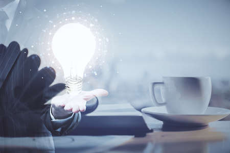 Double exposure of bulb drawing and desktop with coffee and items on table background. Concept of ideas.の写真素材