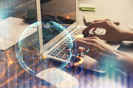 Double exposure of woman hands working on computer and world map hologram drawing. International...