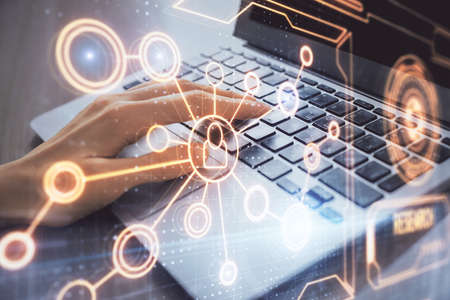 Double exposure of woman hands typing on computer and social network theme hologram drawing. People...