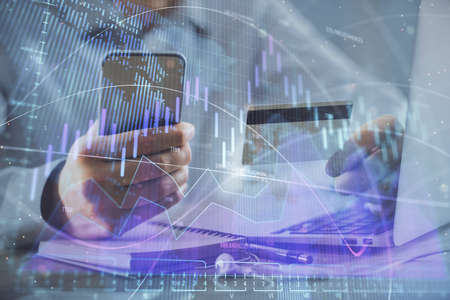 Double exposure of man hands holding a credit card and Forex graph drawing. Stock trading and...
