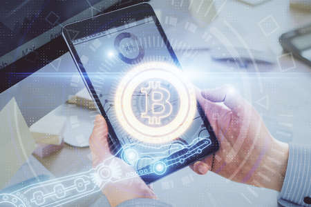 Double exposure of mans hands holding and using a phone and crypto currency blockchain theme...