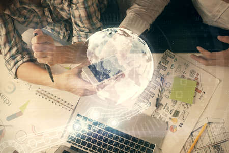 Double exposure of map drawing and man and woman working together holding and using a mobile device. Planet tech concept.の写真素材