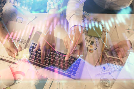 Multi exposure of man and woman working together and forex graph hologram drawing. Financial analysis concept. Computer background. Top View.の写真素材