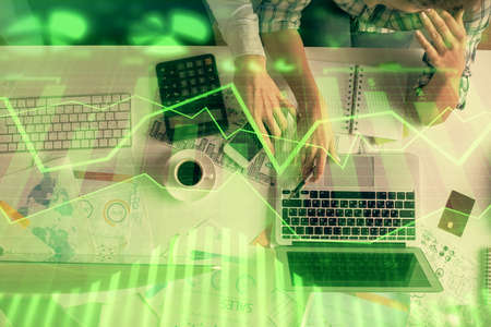 Double exposure of man and woman working together and financial graph hologram drawing. market...