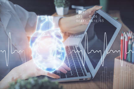 Double exposure of woman hands typing on computer and heart hologram drawing. Education concept.の写真素材