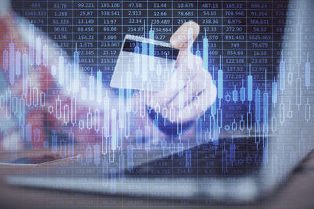 Double exposure of man hands holding a credit card and Forex graph drawing. Stock trading and...