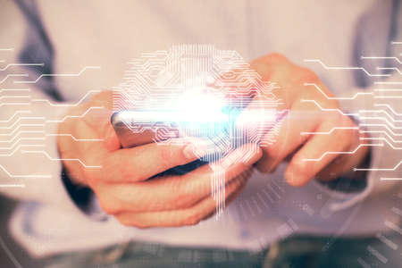 Double exposure of mans hand holding and using a digital device and brain hologram drawing. Data...