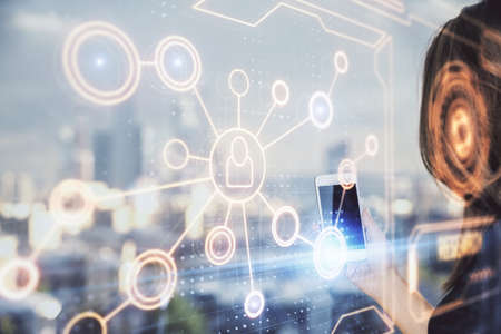 Double exposure of social network sketch hologram and woman holding and using a mobile device.の写真素材