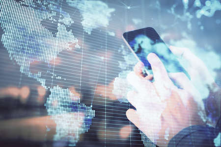 Double exposure of mans hands holding and using a phone and international business theme drawing.