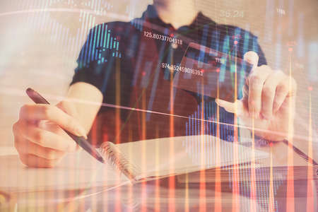 Double exposure of man hands holding a credit card and Forex graph drawing. Stock trading and...