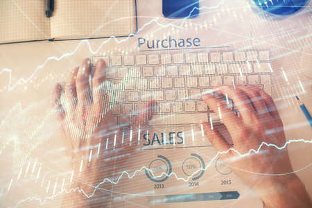 Double exposure of mans hands typing over laptop keyboard and forex chart hologram drawing. Top...