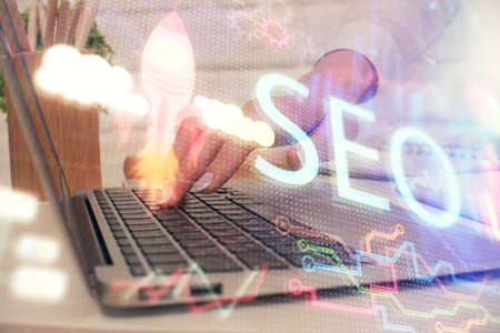 Double exposure of woman hands working on computer and seo hologram drawing. internet search...