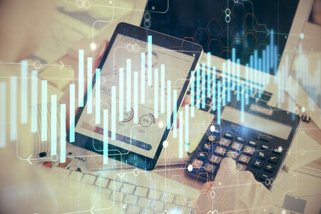 Double exposure of mans hands holding and using a digital device and forex graph drawing. Financial...