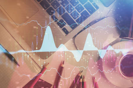 Double exposure of financial chart drawing over table background with computer. Concept of research...