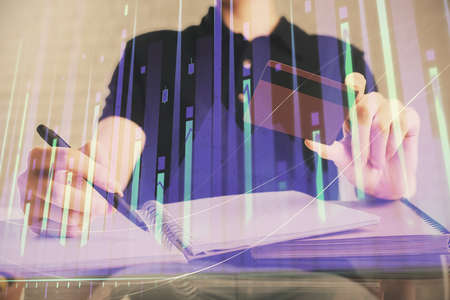 Double exposure of man hands holding a credit card and Forex graph drawing. Stock trading and...
