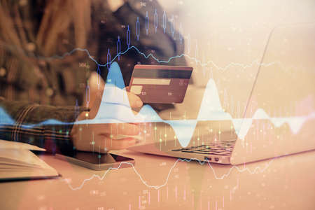 Multi exposure of woman on-line shopping holding a credit card and financial graph drawing. Stock...