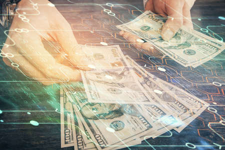 Double exposure of technology drawing hologram and us dollars bills and man hands. Data concept