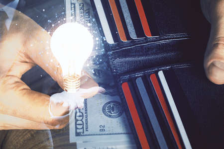 Multi exposure of bulb drawing hologram and USA dollars bills and man hands. Business Idea concept.