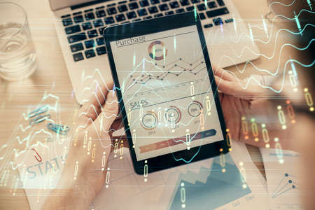 Double exposure of man's hand holding and using a digital device and forex graph drawing. Financial...