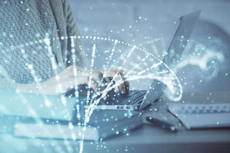 Double exposure of woman hands typing on computer and DNA hologram drawing. Medical education...