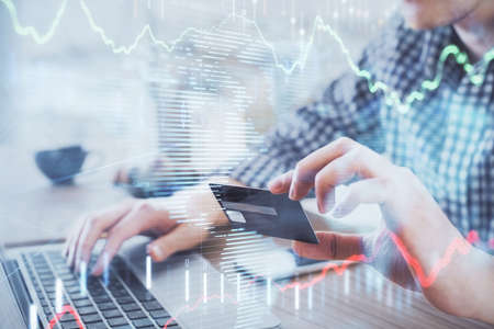 Double exposure of man hands holding a credit card and Forex graph drawing. Stock trading and...
