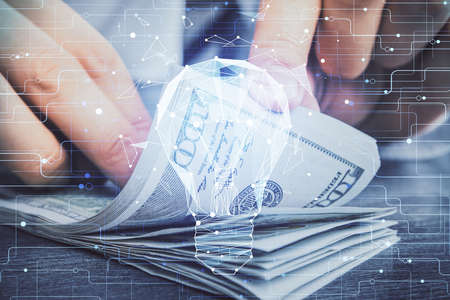 Multi exposure of bulb drawing hologram and USA dollars bills and man hands. Business Idea concept.の写真素材