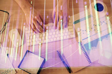 Multi exposure of man's hands typing over computer keyboard and forex graph hologram drawing. Top view. Financial markets concept.の写真素材