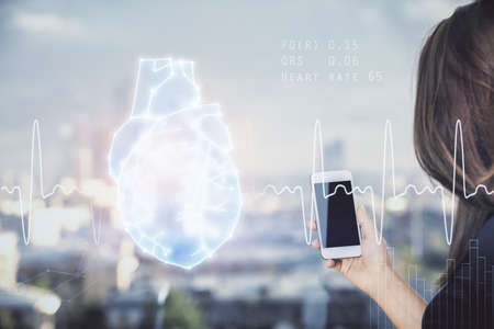 Double exposure of heart sketch hologram and woman holding and using a mobile device. Medical education concept.の写真素材