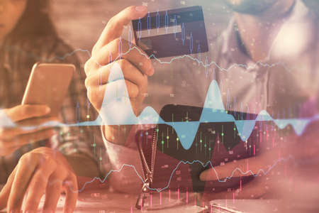 Double exposure of man and woman on-line shopping holding a credit card and forex graph hologram...