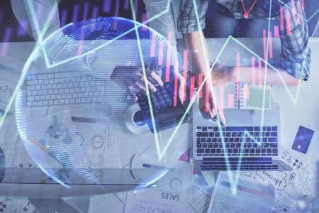 Double exposure of man and woman working together and financial graph hologram drawing. market...
