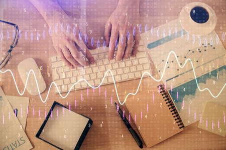 Multi exposure of man's hands typing over computer keyboard and forex graph hologram drawing. Top...
