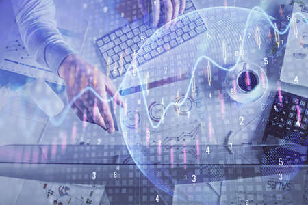 Multi exposure of man's hands typing over computer keyboard and forex graph hologram drawing. Top...