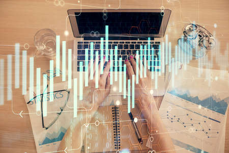 Double exposure of woman hands working on computer and forex graph hologram drawing. Top View....