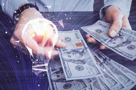 Multi exposure of bulb drawing hologram and USA dollars bills and man hands. Business Idea concept.の写真素材