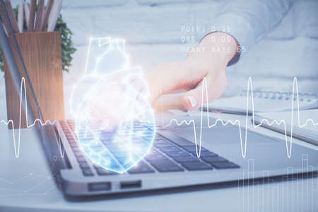 Double exposure of woman hands typing on computer and heart hologram drawing. Education concept.の写真素材