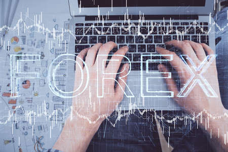 Double exposure of man's hands typing over laptop keyboard and forex chart hologram drawing. Top view. Financial markets concept.の写真素材