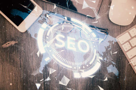 Double exposure of SEO hologram drawing over desktop. Top view. Search optimization concept.の写真素材