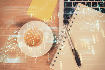 Double exposure of financial chart drawing over table background with computer. Concept of research and analysis. Top view.の写真素材