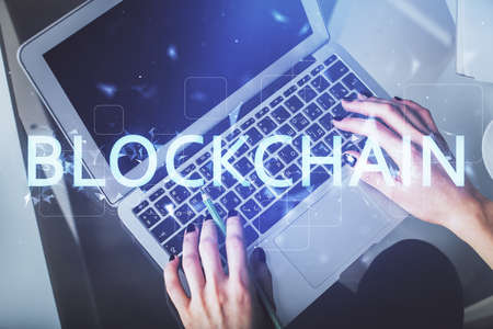 Double exposure of woman hands working on computer and blockchain theme hologram drawing. Top View....