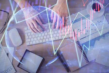 Multi exposure of man's hands typing over computer keyboard and forex graph hologram drawing. Top...