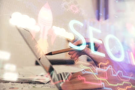 Double exposure of woman hands working on computer and seo hologram drawing. internet search...