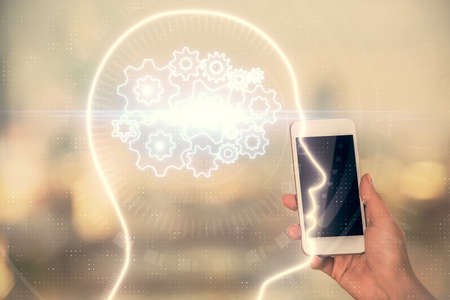 Double exposure of brain sketch hologram and woman holding and using a mobile device.